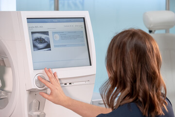 Woman doctor specialist in vision problems sitting in front of ophthalmic diagnostic machine in a...