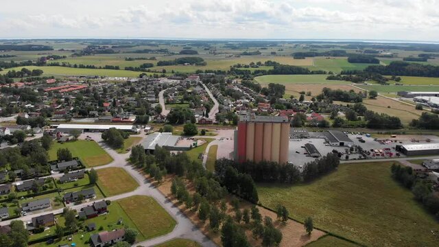 Aerial dolly out landscape shot of Lantmännen Lantbruk agribusiness industrial structure of farm grain silos for agriculture crops storage in rural Brålanda town Sweden.