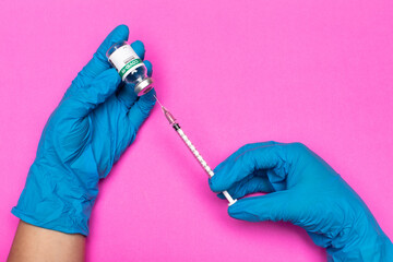 Pink background, medical professional hands on blue hygiene gloves injecting syringe needle into...