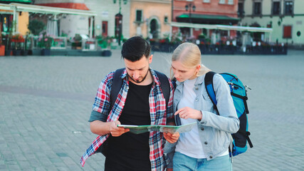 Young couple of tourists with map walking and looking for new historical place in city center. They...