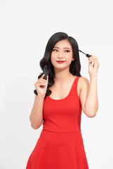 Portrait of pretty young woman applying mascara using lash brush