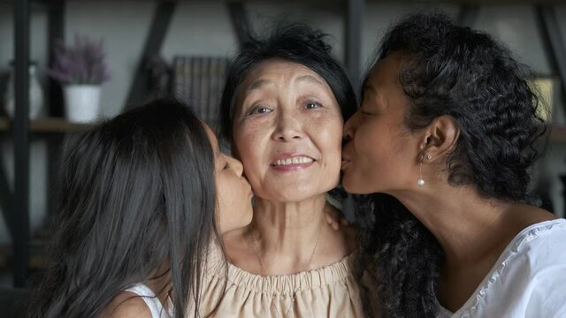 mixed race mom and daughter kiss their grandma