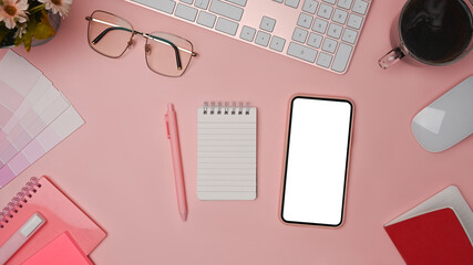 Smart phone, coffee cup, glasses and notebook on pink background. Female workspace.