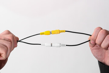 the wires connected by an RCA jack are white and yellow in male hands. on a white background. copy space
