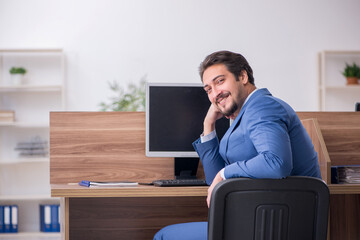 Young male employee sitting at workplace