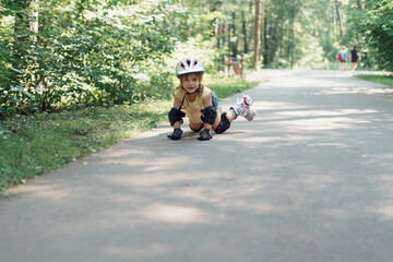 child girl in protective sportswear fell down while rollerblading. kid does not feel pain and smiles. safe children's sports