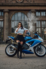 Obraz na płótnie Canvas Stylish girl with vape and motorbike outside on road