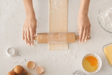 Woman rolling out dough on kitchen table