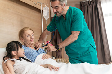 Asian Lovely girl visit and encourage grandmother when The doctor examines a elder patient on patient bed in hospital