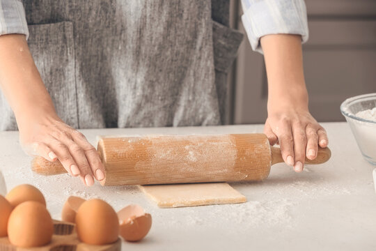 Woman rolling out dough on kitchen table