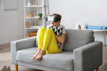 Scared young woman with virtual reality glasses at home