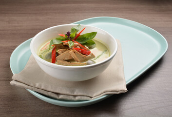 thai spicy chili green curry hot soup with vegetarian meat in bowl blue plate on wood background asian halal vegan menu