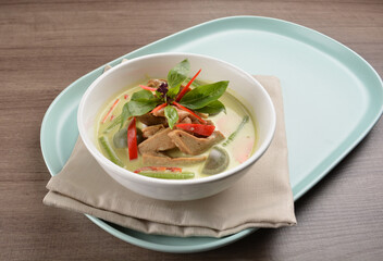 thai spicy chili green curry hot soup with vegetarian meat in bowl blue plate on wood background asian halal vegan menu