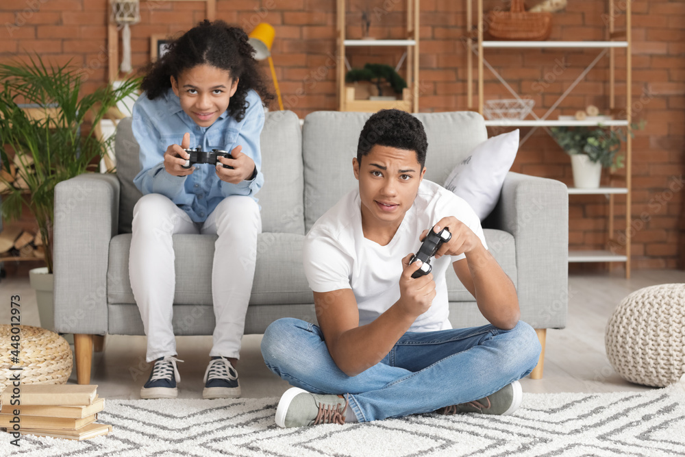 Wall mural african-american brother and sister playing video game at home