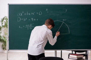 Schoolboy studying geometry in front of blackboard