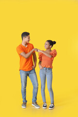 African-American brother and sister bumping fists on color background