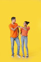 Obraz premium African-American brother and sister bumping fists on color background