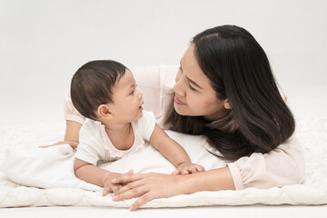 Mother and baby girl look at each other   on isolated background.