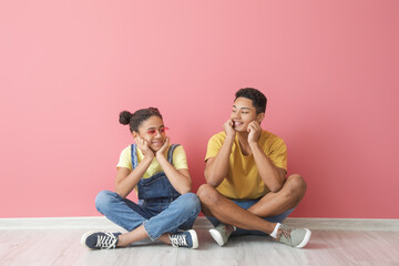 African-American brother and sister sitting near color wall