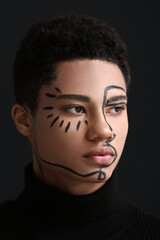 Young African-American guy with paint on face against dark background