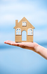 Girl holding the symbol of the house over the sea
