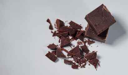 Broken pieces of chocolate and cocoa powder on a white background