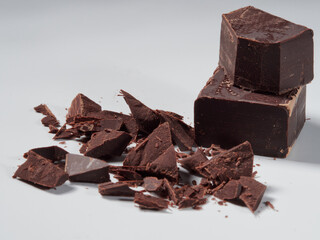 Broken pieces of chocolate and cocoa powder on a white background