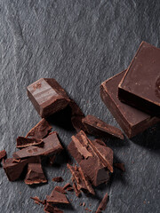 Broken pieces of chocolate and cocoa powder on a black background