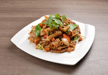 wok stir fried kway teow rice noodle mee goreng with vegetable in spicy soy chilli sauce on wood background asian halal vegan menu