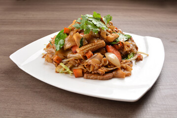 wok stir fried kway teow rice noodle mee goreng with vegetable in spicy soy chilli sauce on wood background asian halal vegan menu