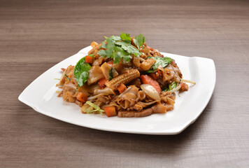 wok stir fried kway teow rice noodle mee goreng with vegetable in spicy soy chilli sauce on wood background asian halal vegan menu
