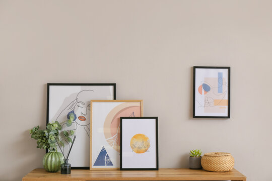 Stylish pictures on shelf near light wall