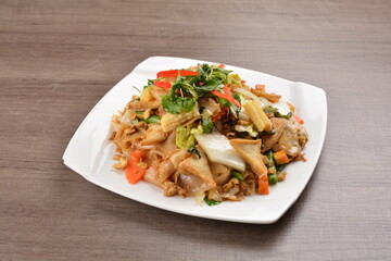wok stir fried kway teow rice noodle mee goreng with vegetable in spicy soy chilli sauce on wood background asian halal vegan menu