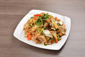 wok stir fried kway teow rice noodle mee goreng with vegetable in spicy soy chilli sauce on wood background asian halal vegan menu