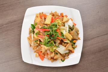 wok stir fried kway teow rice noodle mee goreng with vegetable in spicy soy chilli sauce on wood background asian halal vegan menu