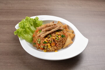 vegetarian nasi goreng fried rice with pineapple, vegetables meat in spicy chilli sambal sauce on wood background asian halal vegan menu