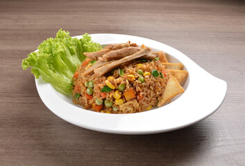 vegetarian nasi goreng fried rice with pineapple, vegetables meat in spicy chilli sambal sauce on wood background asian halal vegan menu