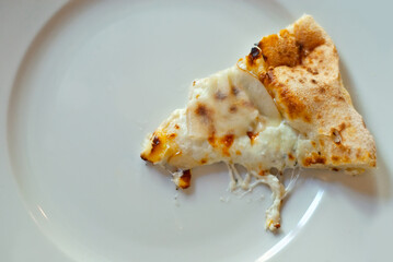 Triangular slice of pizza on a white plate close up. Pizza with cheese, pear and pine nuts.