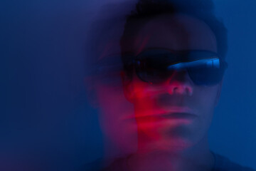 man wearing sunglasses in neon party light, male portrait with motion blur