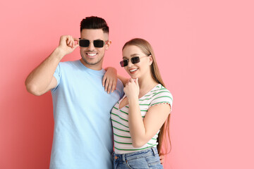 Young couple wearing stylish sunglasses on color background