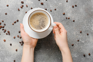 Woman with cup of coffee and beans on grunge background
