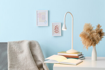 Lamp with books and vase on table near color wall