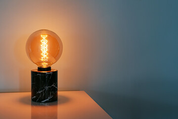 Glowing lamp on table in dark room