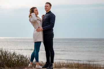 Portrait of pretty young couple wearing trendy spring clothes. Two lovers posing against beach background in evening.