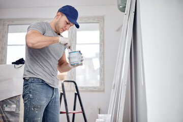 Young adult man painting on a DIY budget renovation of his new home apartment.