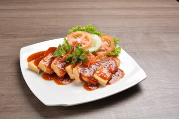deep fried bean curd tofu with spicy sambal chilli sauce on wood background asian halal vegan menu