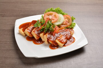 deep fried bean curd tofu with spicy sambal chilli sauce on wood background asian halal vegan menu