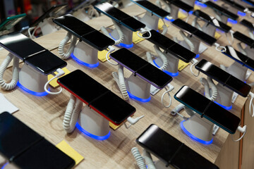 There are many different phones on the counter in the store. Close-up. Side view.