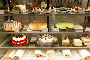 Delicious variety of cakes and pastries in a glass display case. Front view.
