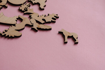 Wooden puzzle on a pink background. Puzzle pieces in the shape o